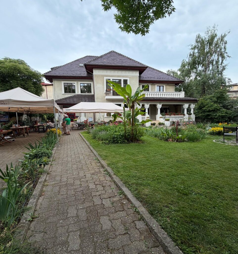 A brick path with plants and a house in the background AI-generated content may be incorrect.